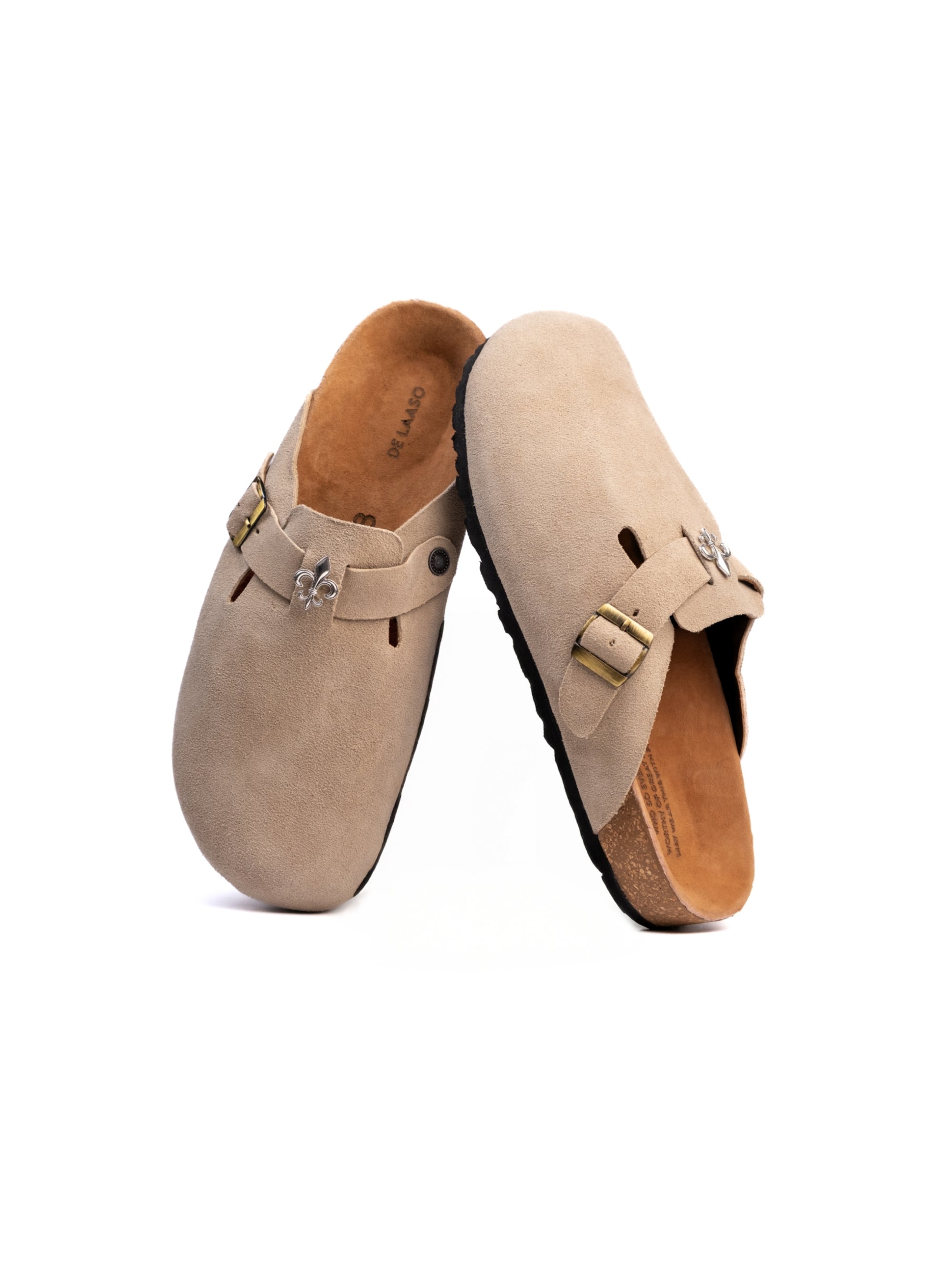 Pair of beige suede clogs with buckles on a white background