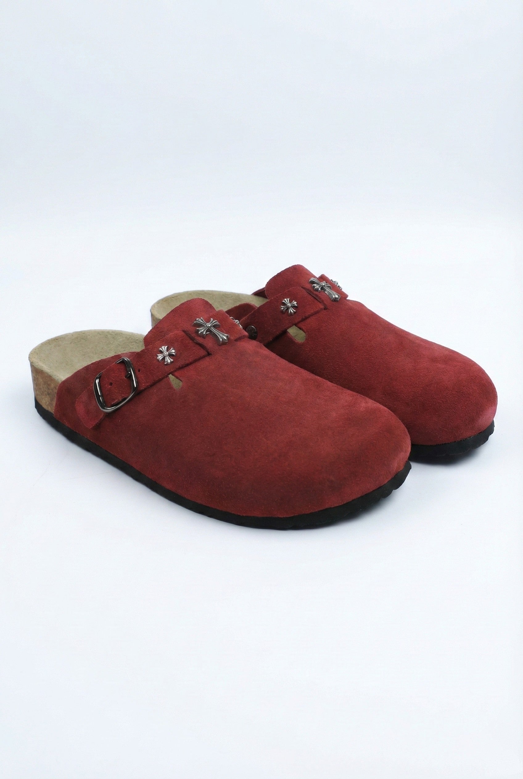 Pair of red suede clogs with a buckle on a white background